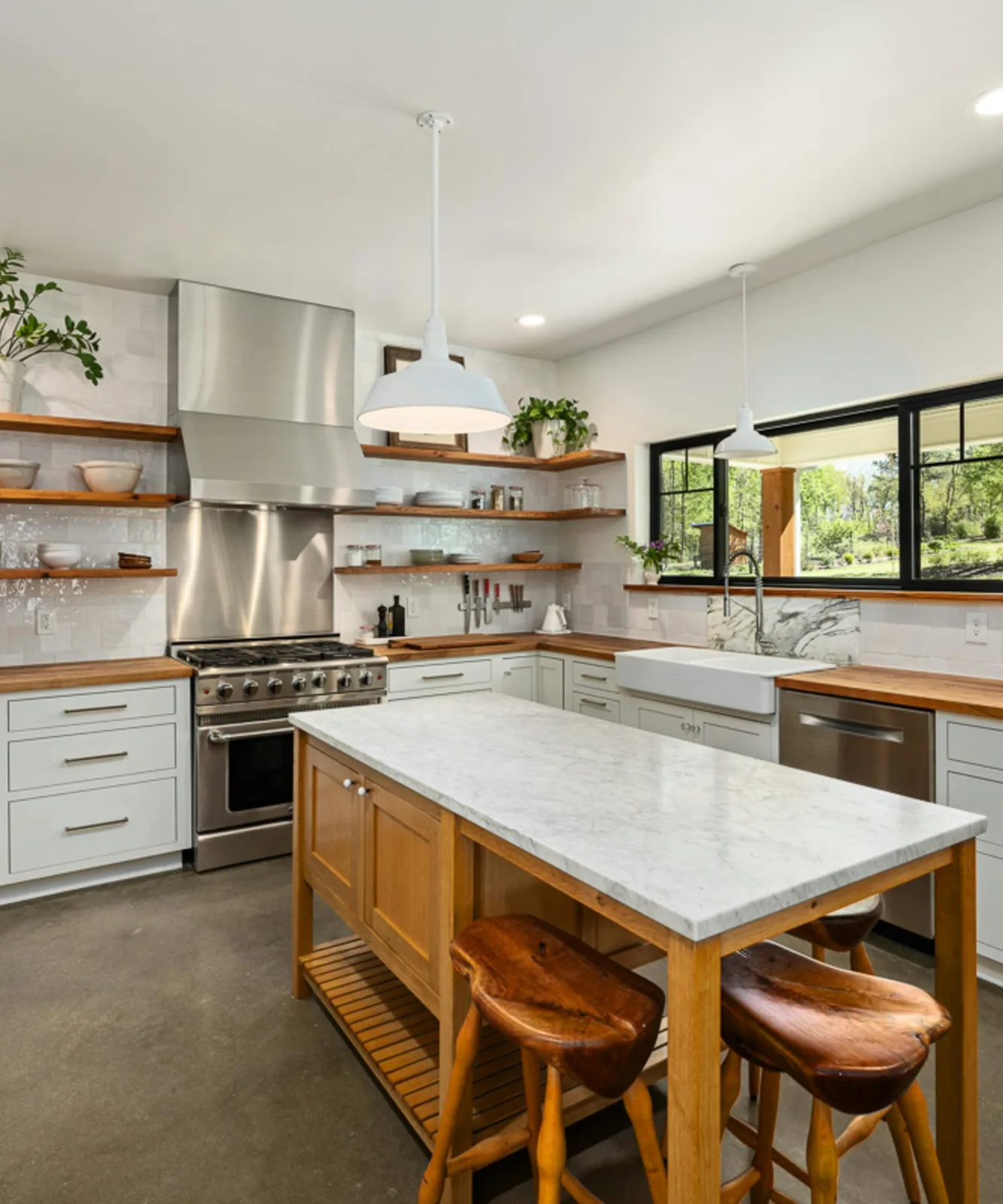 Bright kitchen with marble island, open wood shelves, and natural daylight