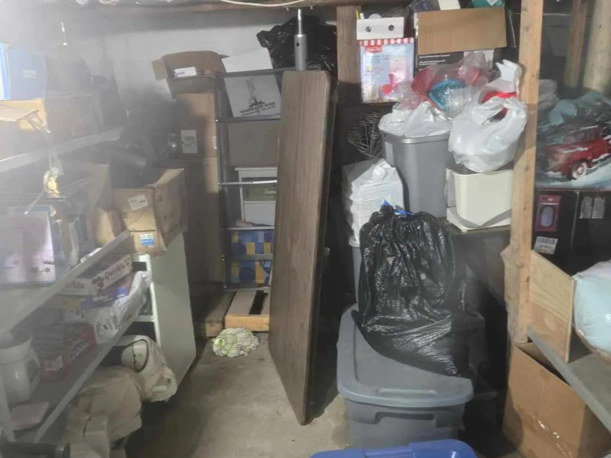 Basement packed with shelving, boxes, and storage totes before a cleanout