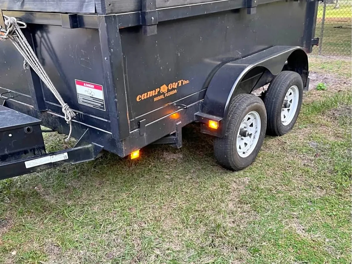 Scribner's black tandem-axle dump trailer, empty, parked on grass